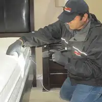 Bed bug inspection technician checking a mattress and bed frame for signs of infestation in New Orleans, LA