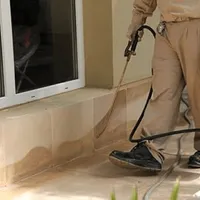 General pest control technician spraying exterior perimeter around a home in New Orleans, LA