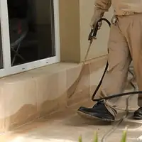 General pest control technician spraying exterior perimeter around a home in New Orleans, LA