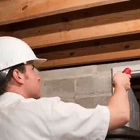 Termite inspection technician checking a basement wall and framing for termite activity in New Orleans, LA