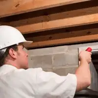 Termite inspection technician checking a basement wall and framing for termite activity in New Orleans, LA